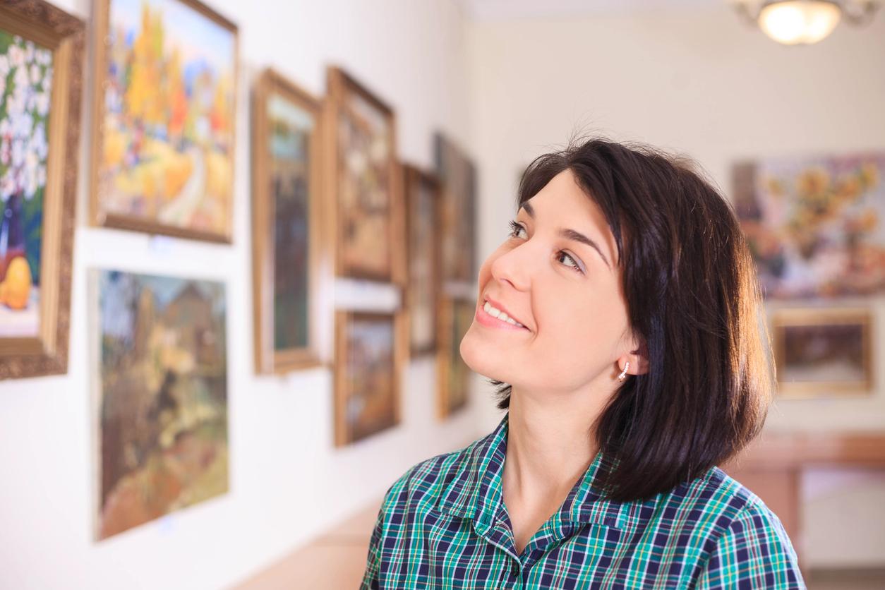 Pessoa observando atentamente quadros em uma galeria de arte, ilustrando o artigo “6 dicas para preservar seus quadros.