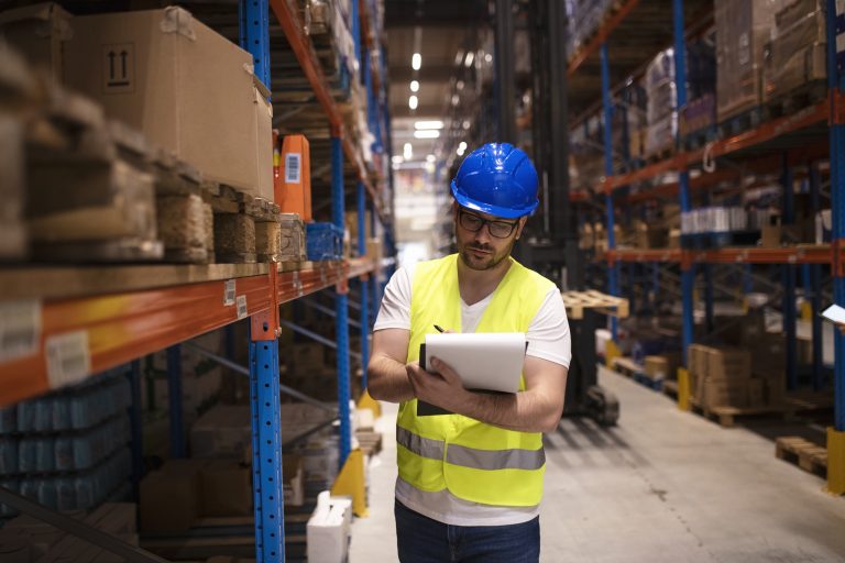 Operador logístico em centro de distribuição realizando conferência de mercadorias e controle de estoque